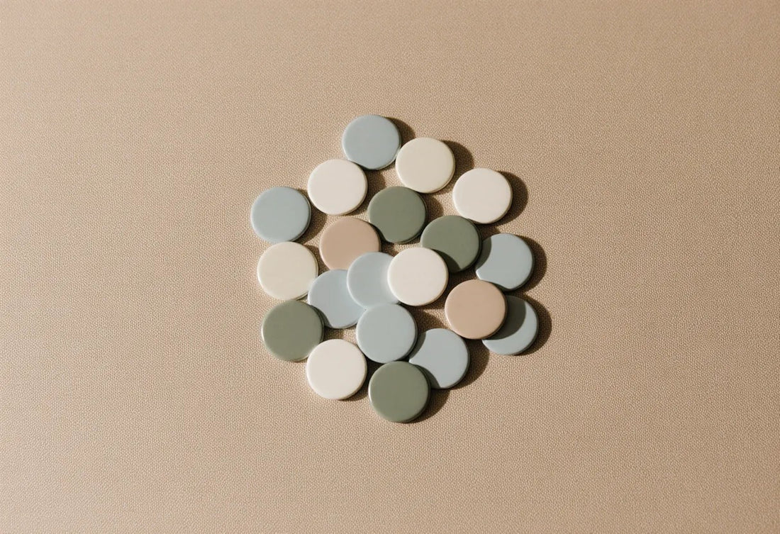 A cluster of plain round pin badges in muted colours on warm linen