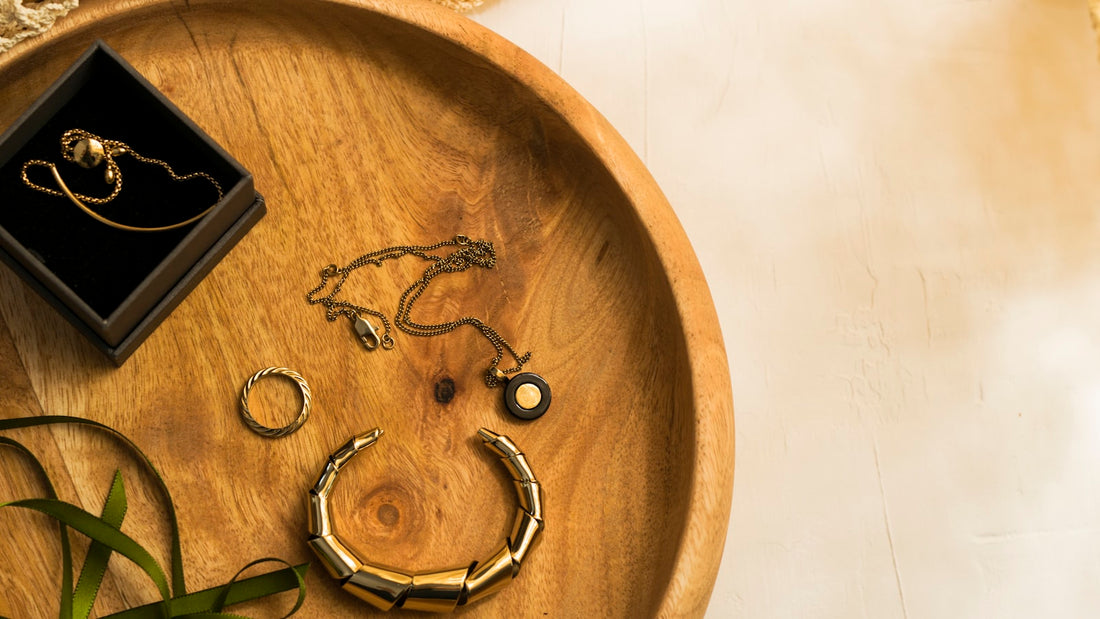 Gold jewellery, rings and a bracelet arranged on a round wooden tray
