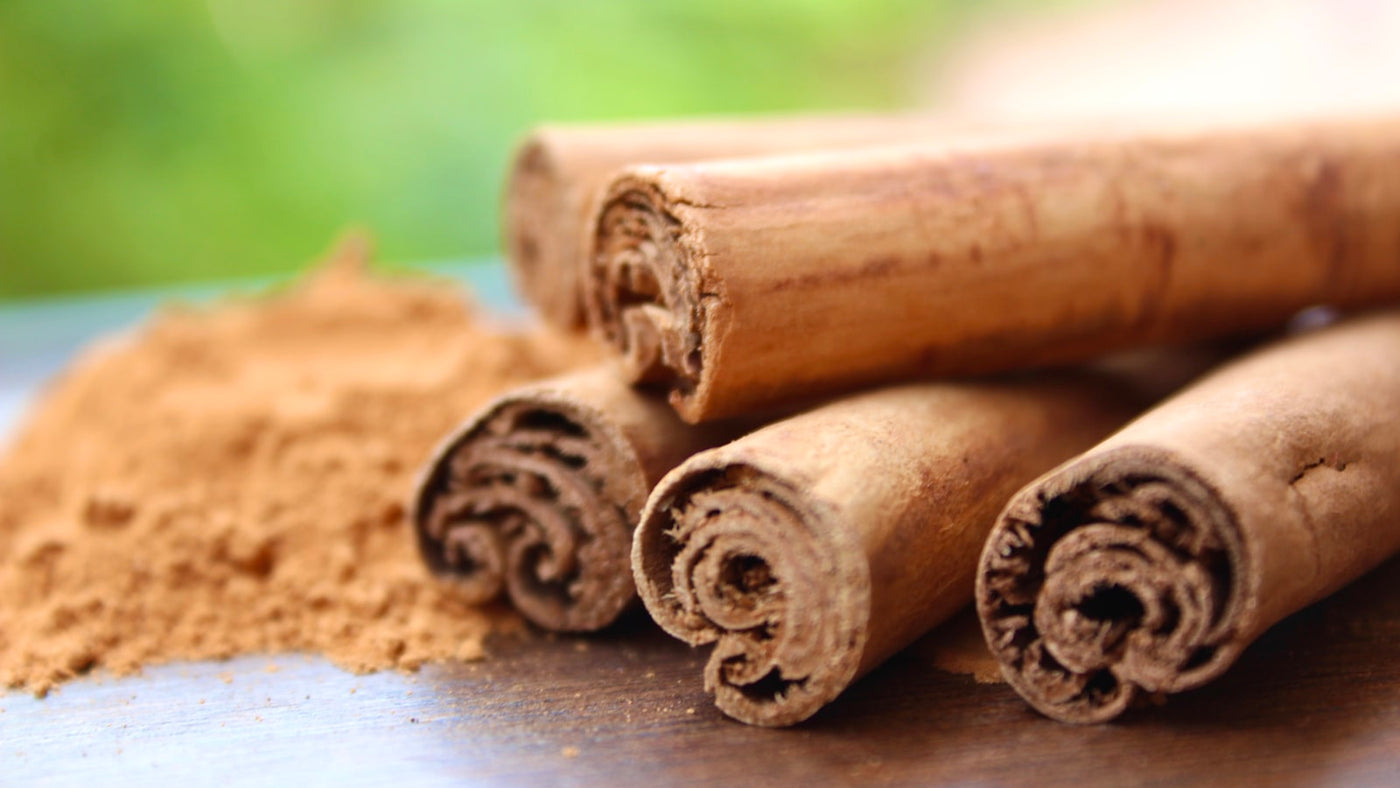 Rolled cinnamon sticks and ground cinnamon on a warm neutral surface