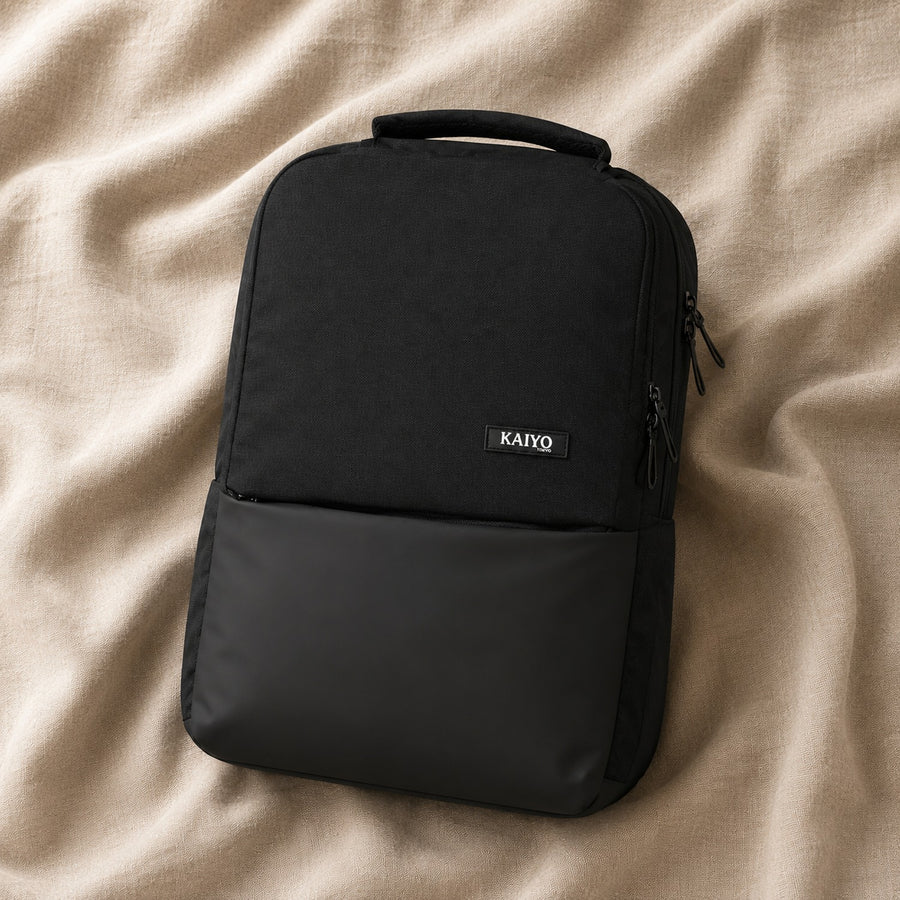 Ginza30 Laptop Backpack in Black resting on natural oatmeal linen