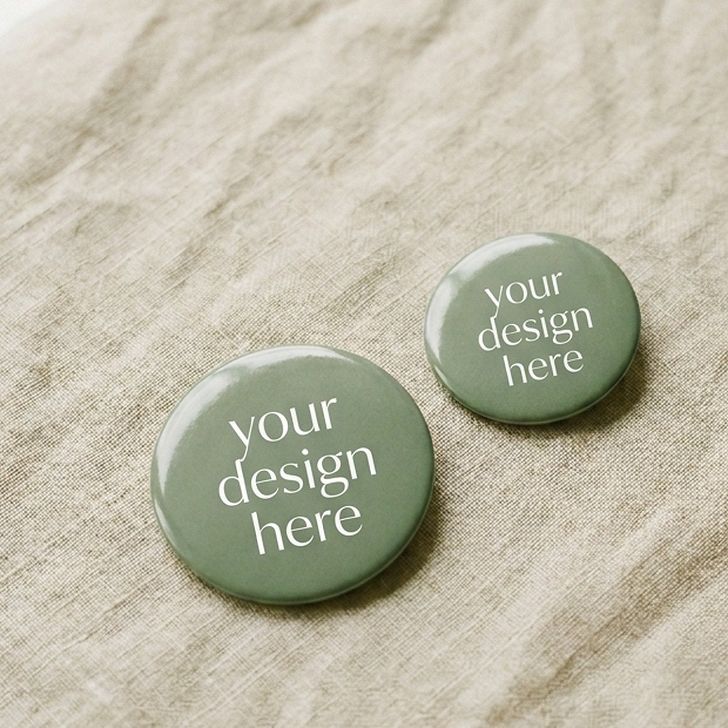 Two sage green Custom Print Badges from Mawlaii Rochcha on warm linen — 44mm and 58mm, glossy laminated finish, ready for your artwork.